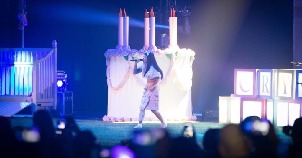 Melanie Martinez stands before a stunning cake, capturing a moment of joy and festivity.