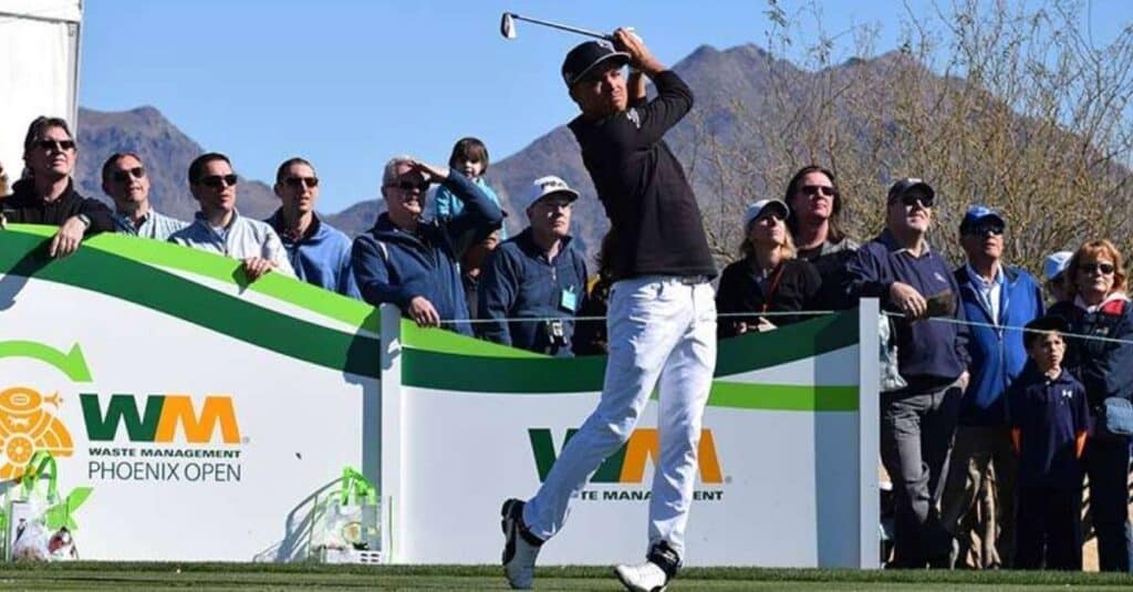 Rickie Fowler swings his golf club, captivating a crowd with his impressive technique and focus during the game.