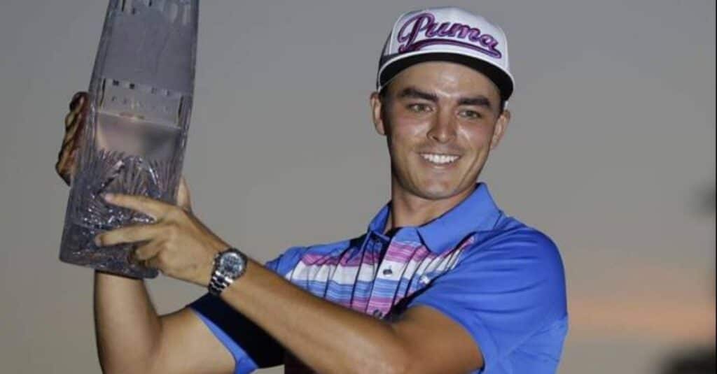 Rickie Fowler stands with a trophy in hand, showcasing his success and dedication in sports.