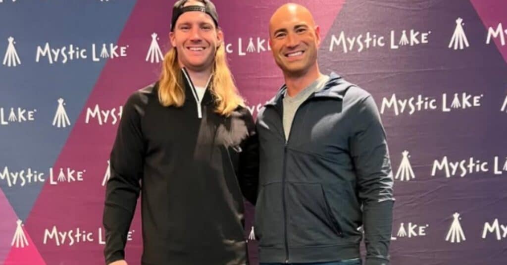 Ben Leber and another man stand together in front of a wall, appearing relaxed and engaged in discussion.