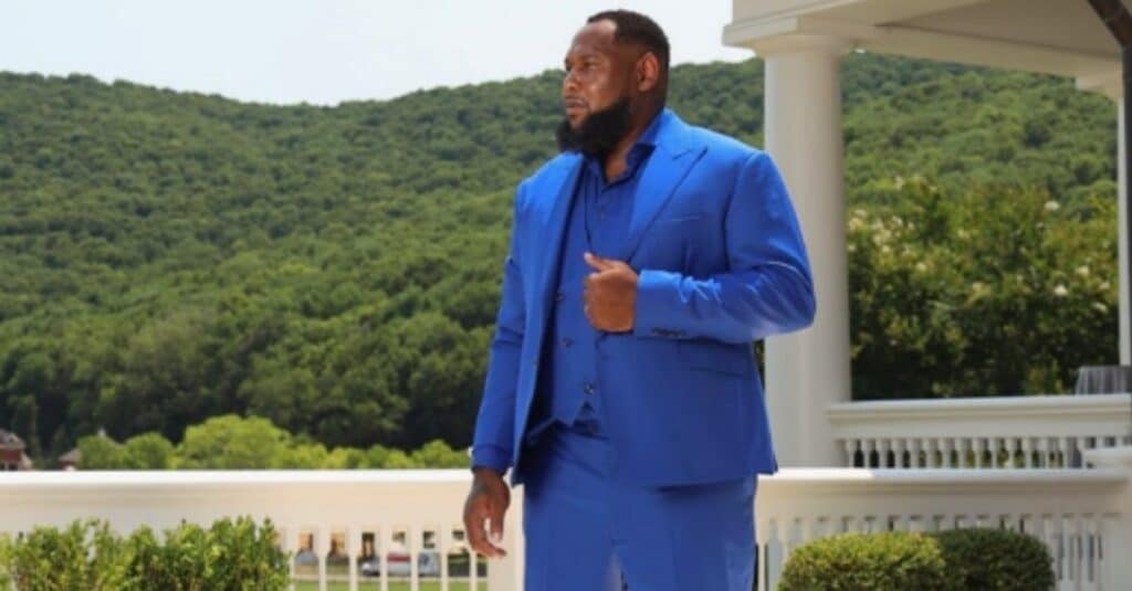 Courtney Beasley stands on a porch, dressed in a blue suit, exuding confidence and style.