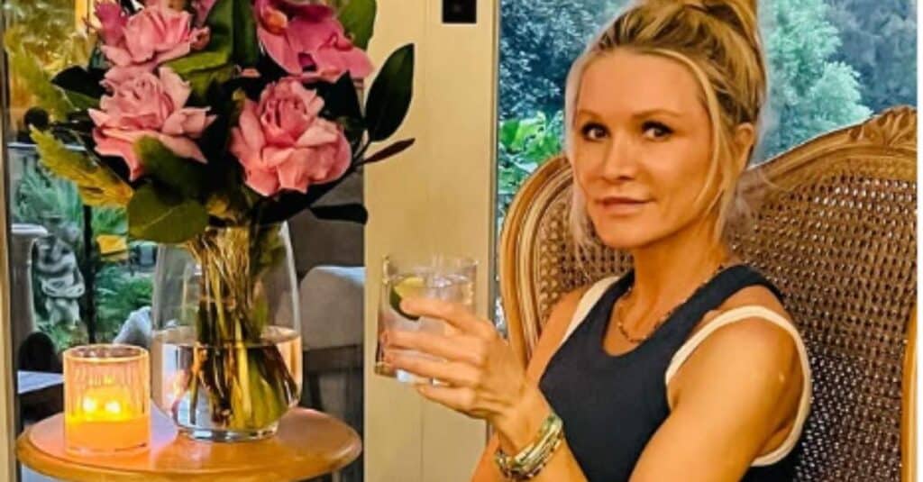 Danielle Spencer enjoys a glass of wine while seated in a chair, accompanied by her family members.