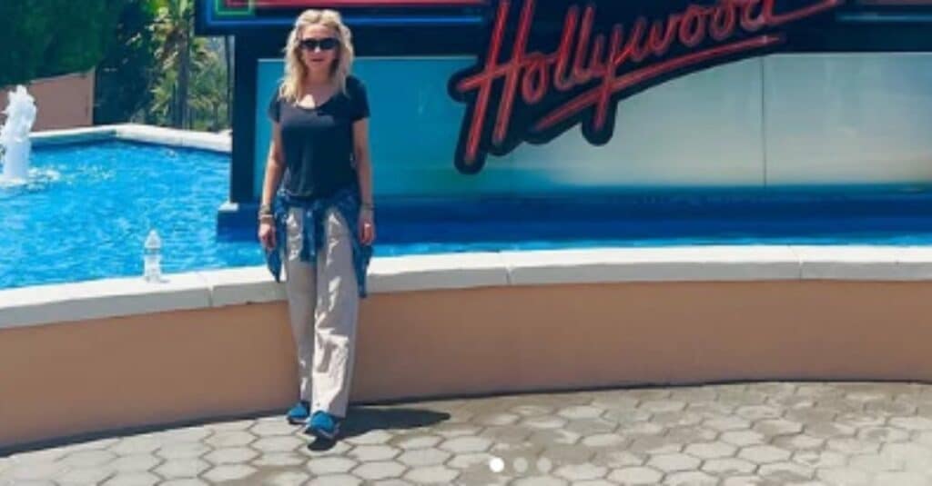 Danielle Spencer poses in front of a fountain, with a prominent sign displaying "Hollywood" nearby.