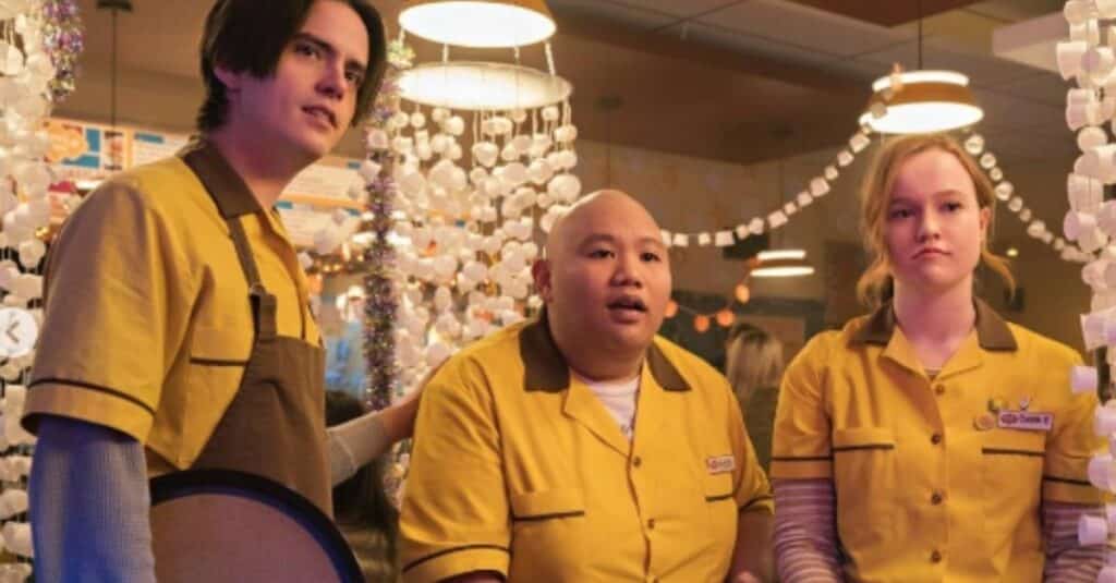 Three people, and in middle is Jacob Batalon wearing yellow shirts stand together, exuding a sense of camaraderie and joy.