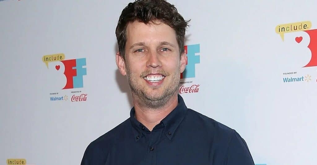 Jon Heder  in a blue shirt, resembling Jon Heder, exudes warmth and friendliness in the image.