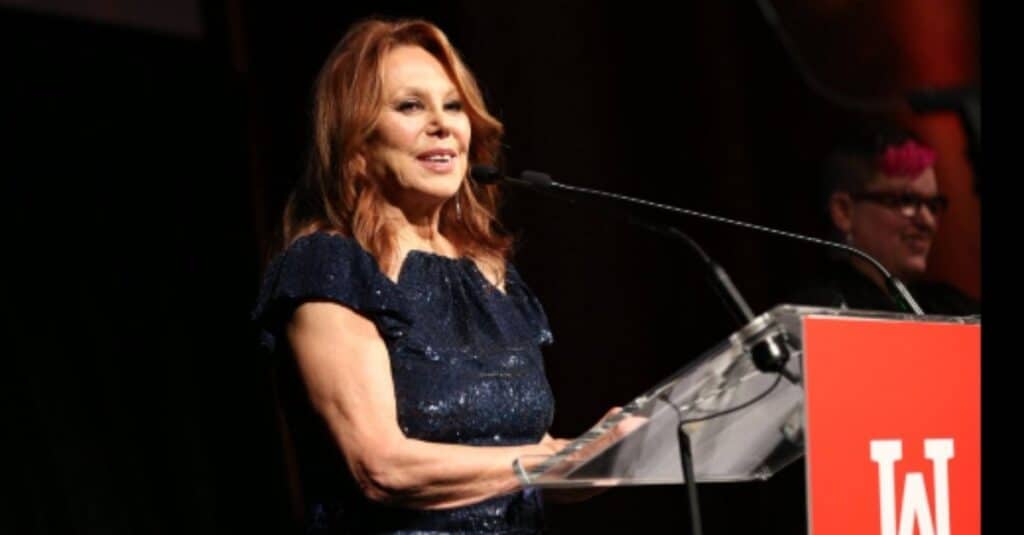 Marlo Thomas addresses the audience from a podium at an event, conveying her thoughts with confidence and poise.